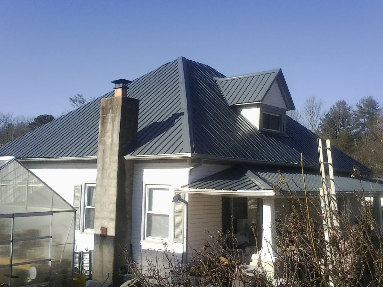 Dark blue standing seam metal roof on a white farmhouse with dormer — Slate & Tile Roof Repair by Roofing Brothers in Oilville