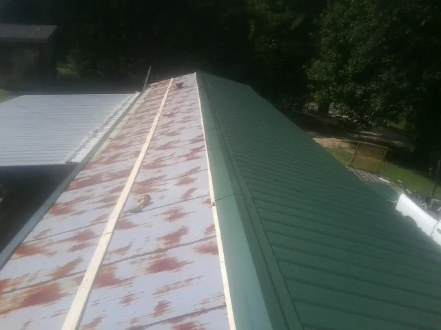 Old rusted panels beside newly installed green metal roofing — Wind Damage Roof Repair by Roofing Brothers in Oilville