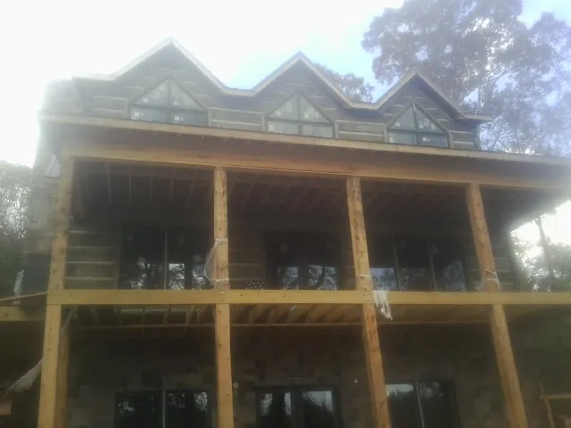 Dormers and porch framing on a large log home under construction — Roof Coating work by our crew in Oilville