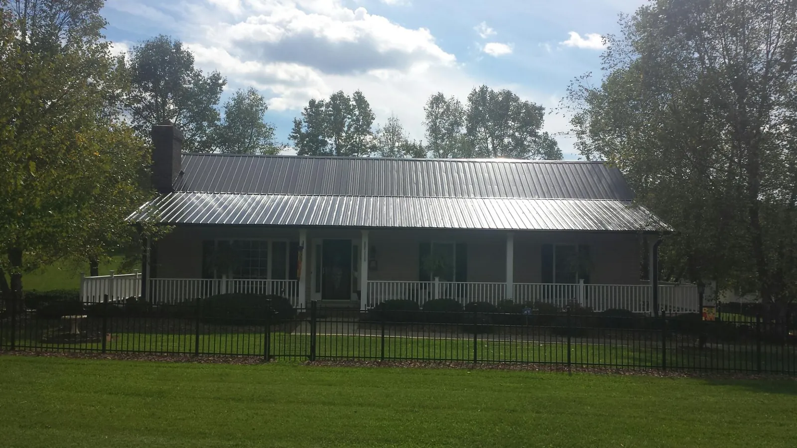 Gray metal roof on a brick ranch with a full width front porch — Gutter Guard Installation work by our crew in Oilville