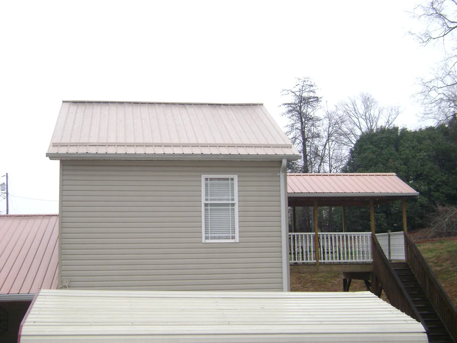 Tan metal roofs on a two story addition and attached porch, from a Roof Replacement job in Oilville